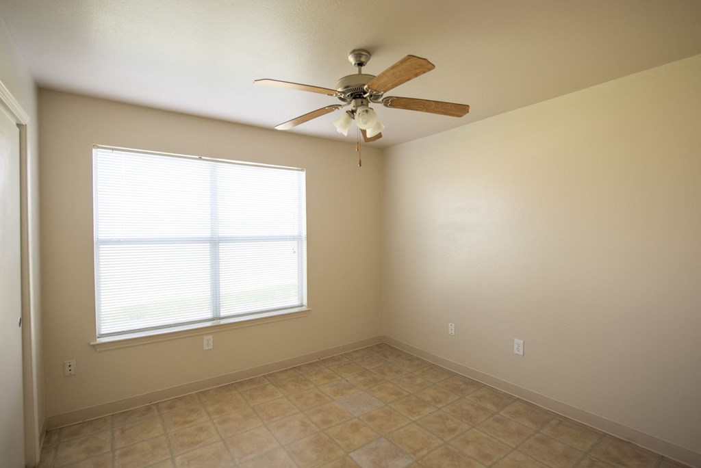 an empty living room with a ceiling fan and a window