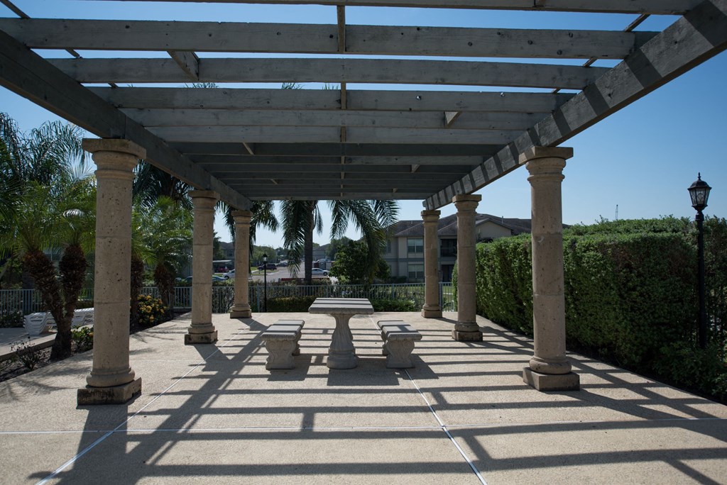 a covered patio with a table and benches