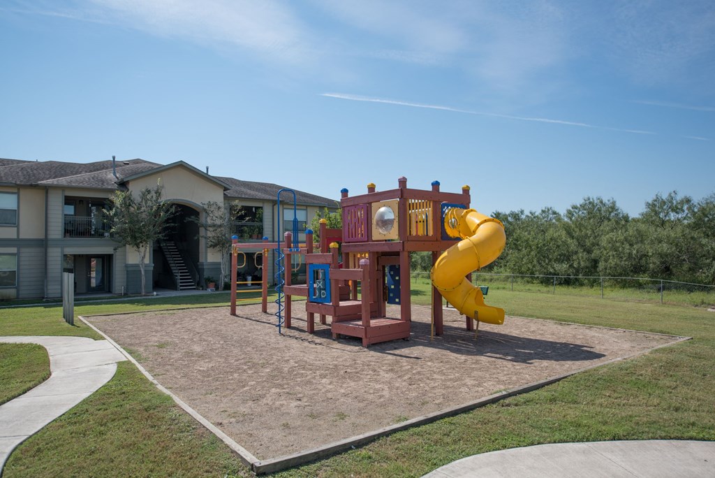 a playground with a yellow slide in front of a building