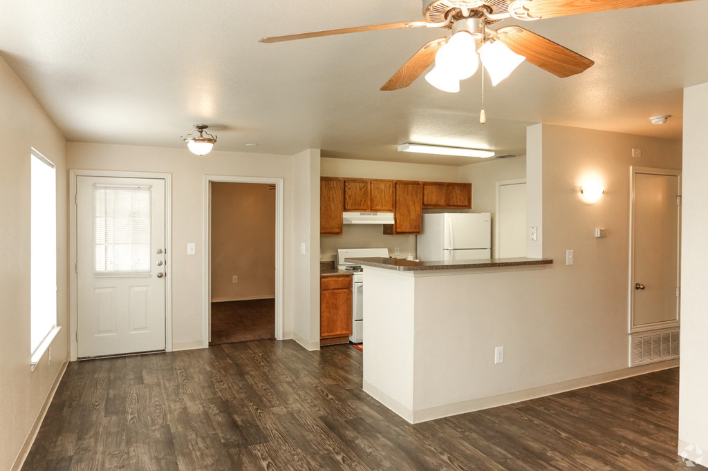 an empty living room and kitchen with a ceiling fan