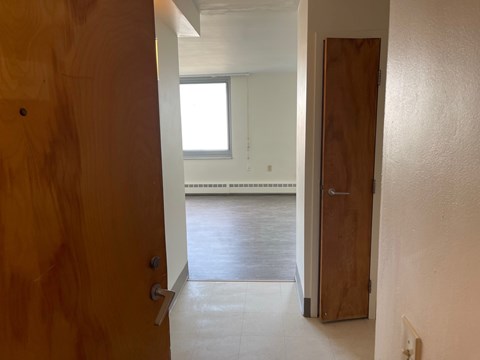 A hallway with a wooden door on the left and a wooden door on the right.