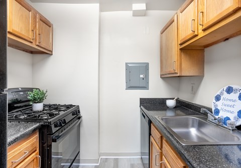 A kitchen with a stove, sink and cabinets.