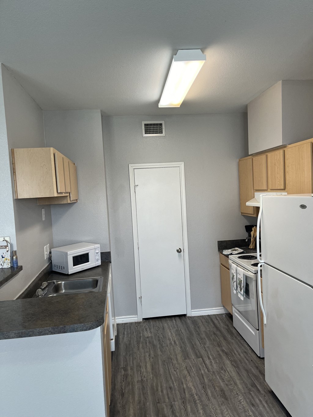 an empty kitchen with white appliances and a refrigerator