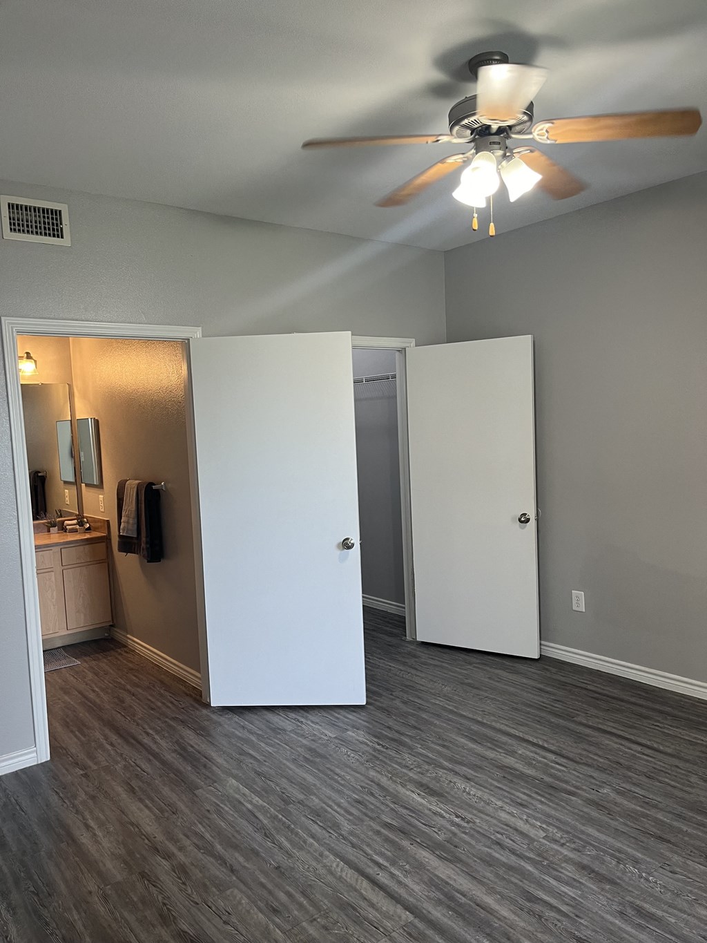 an empty living room with a ceiling fan and a closet
