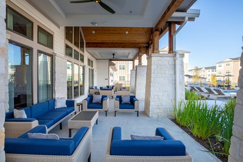 a patio with blue couches and chairs and a pool in the background a patio with blue couches and chairs and a pool in the background at 55 Fifty at Northwest Crossing, Texas, 77092