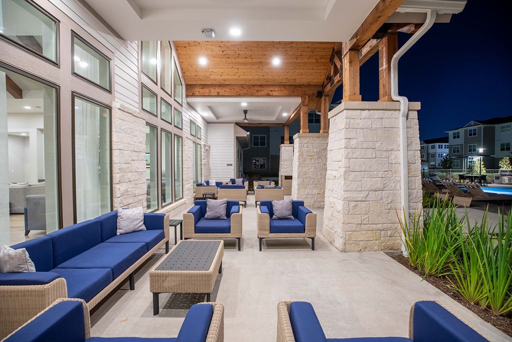 a patio with blue couches and chairs and a pool in the background at 55 Fifty at Northwest Crossing, Houston, 77092
