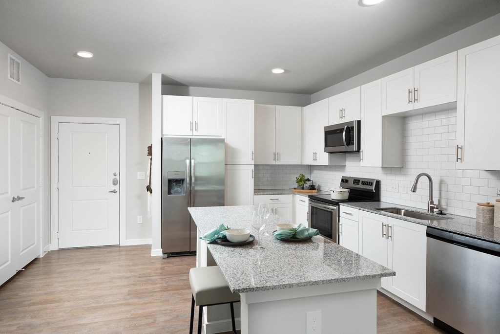 a kitchen with white cabinets and a granite counter top at 55 Fifty at Northwest Crossing, Houston