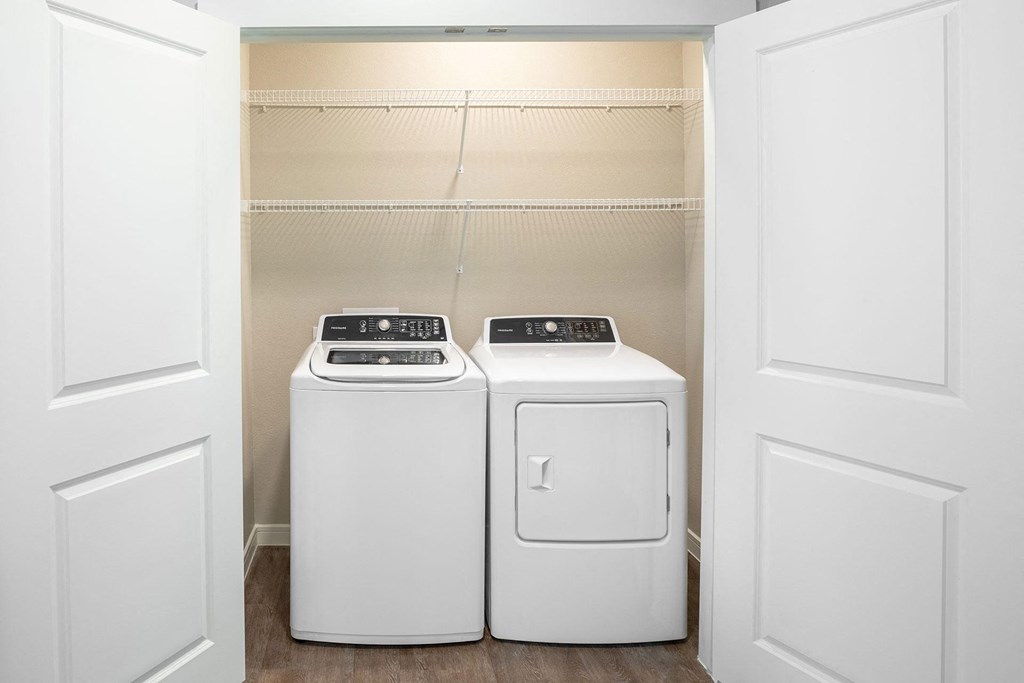 a washer and dryer in a laundry room with white doors at 55 Fifty at Northwest Crossing, Texas, 77092