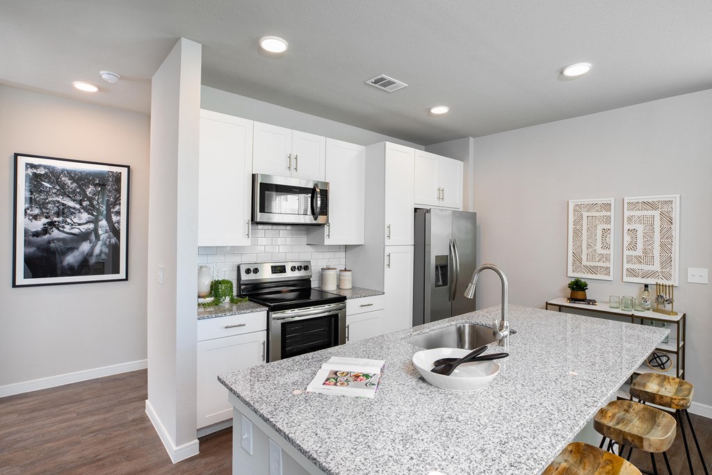 a kitchen with white cabinets and a granite counter top at 55 Fifty at Northwest Crossing, Houston, TX