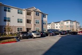 a parking lot full of cars in front of an apartment building at 55 Fifty at Northwest Crossing, Houston Texas