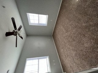 a ceiling with a ceiling fan and two windows