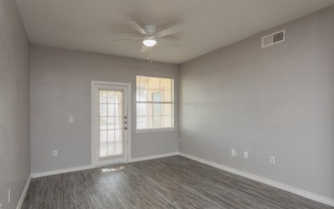 an empty living room with a ceiling fan and a window