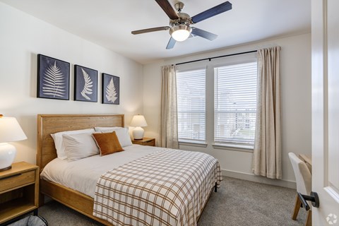 A bedroom with a bed, a ceiling fan, and a chair.