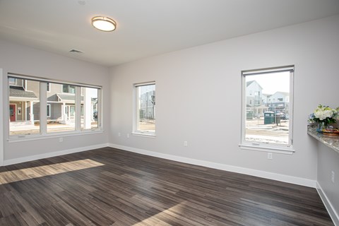 A room with wooden flooring and a window showing a view of a street.