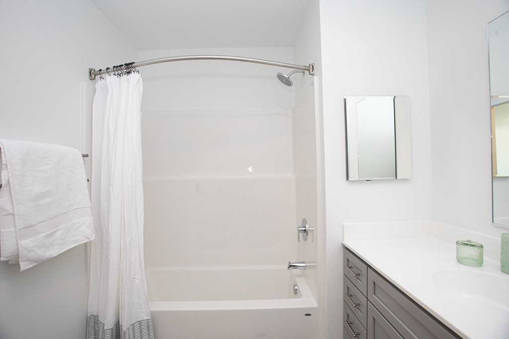 A white bathroom with a white tub and a white towel hanging on the wall.