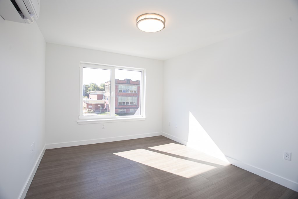A room with a window and a white wall.