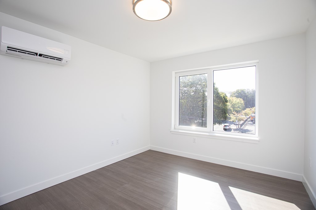 A room with a window and a wall-mounted air conditioner.