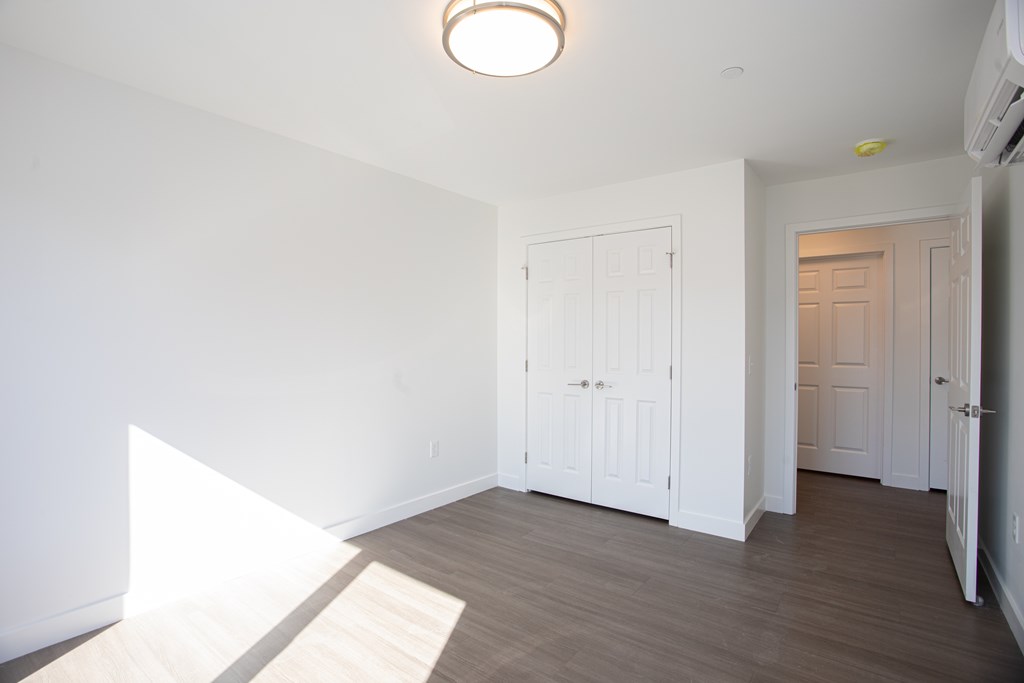 A white room with a wooden floor and a white door.