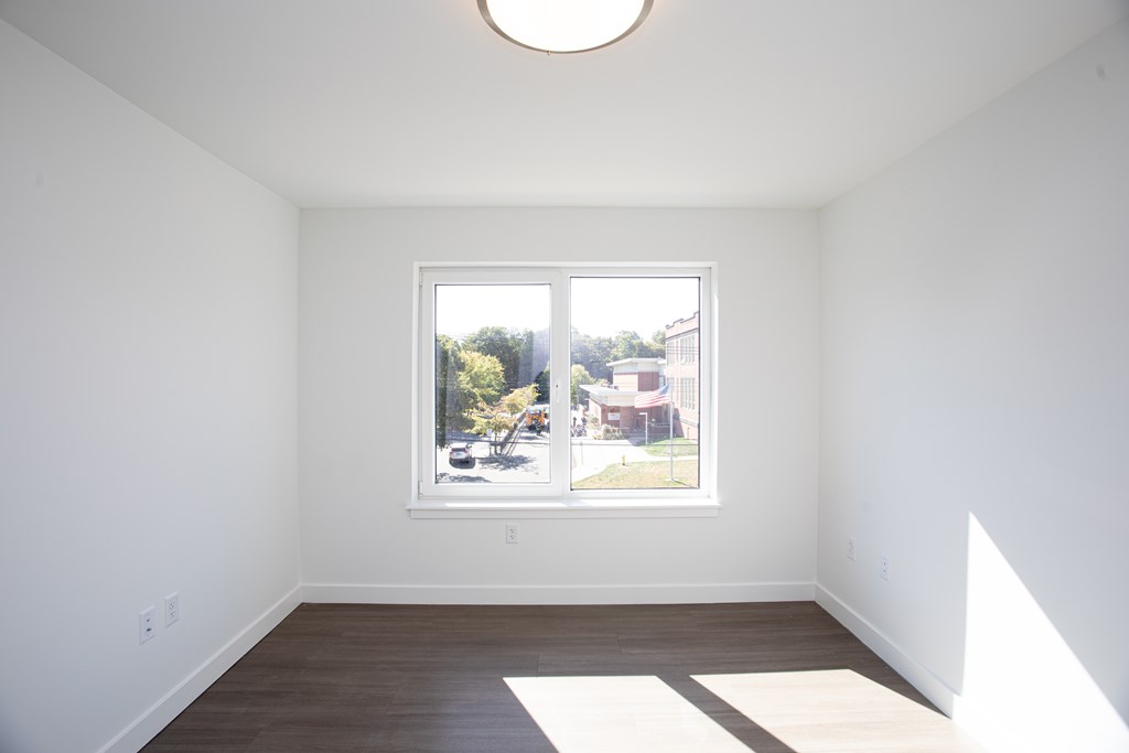 A white room with a window and a picture on the wall.