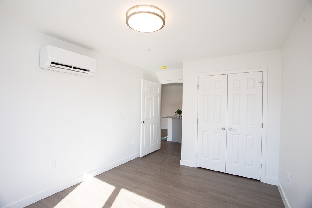 A white room with a ceiling light and an air conditioner unit on the wall.