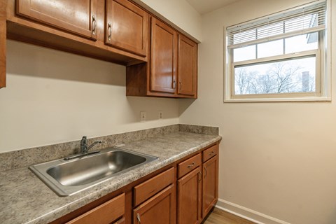 A kitchen with brown cabinets and a silver sink.