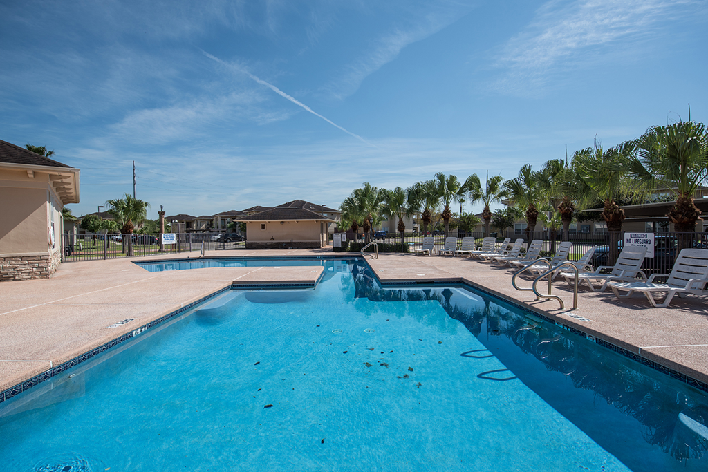 our resort style swimming pool is next to our club house with palm trees
