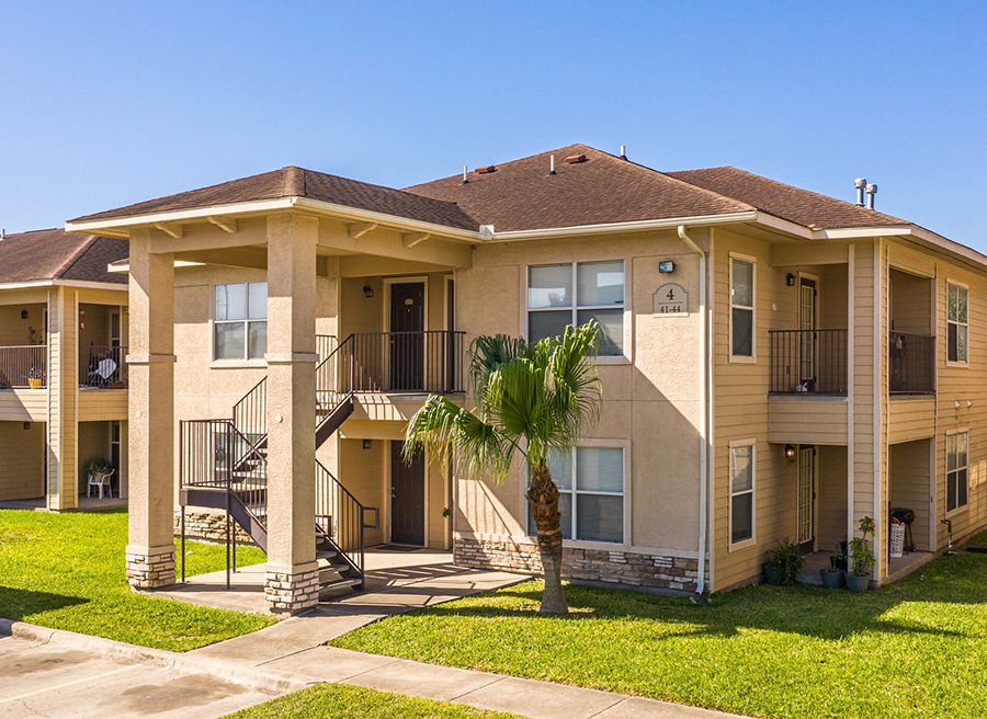 an apartment building with a palm tree in the yard