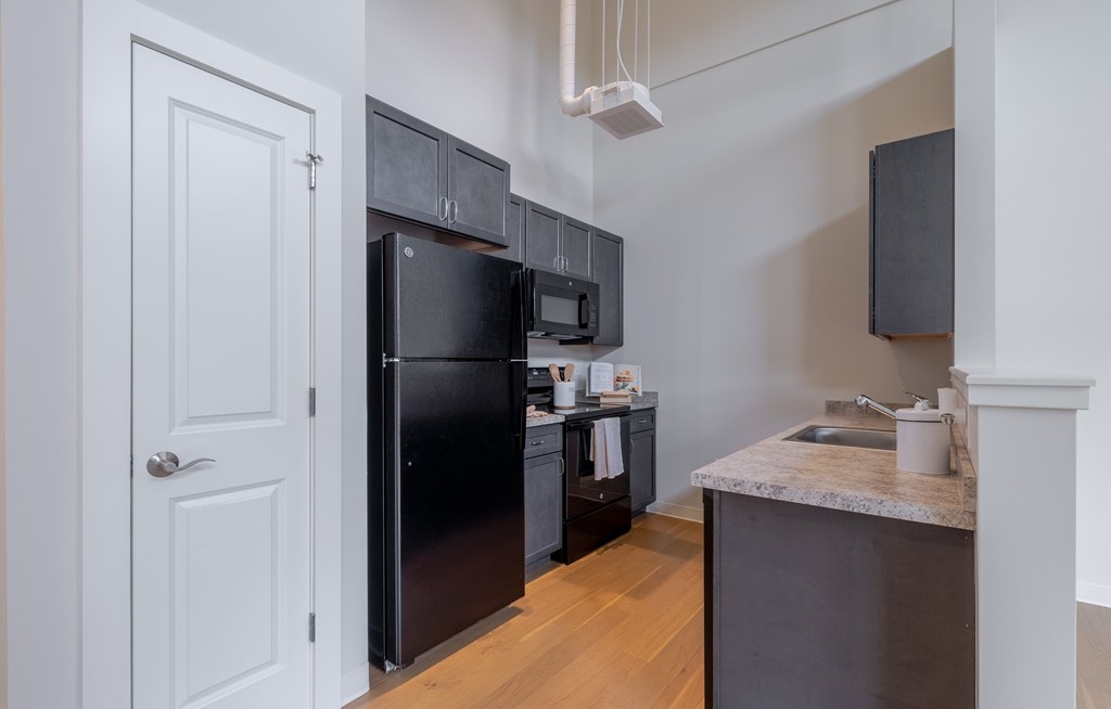 A kitchen with a black fridge and microwave.