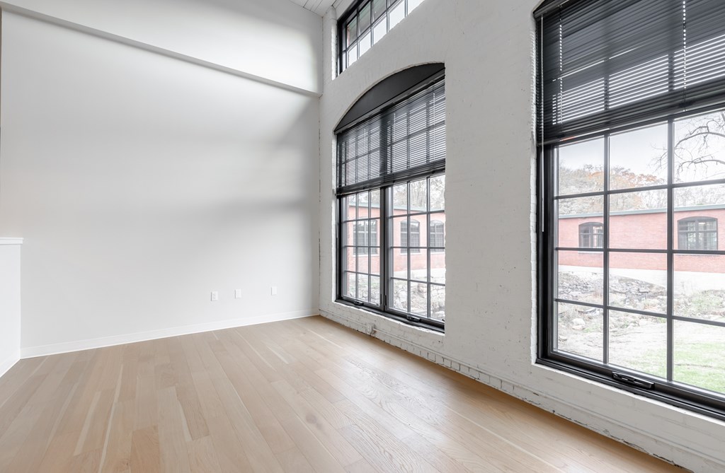 A room with a large window and wooden flooring.