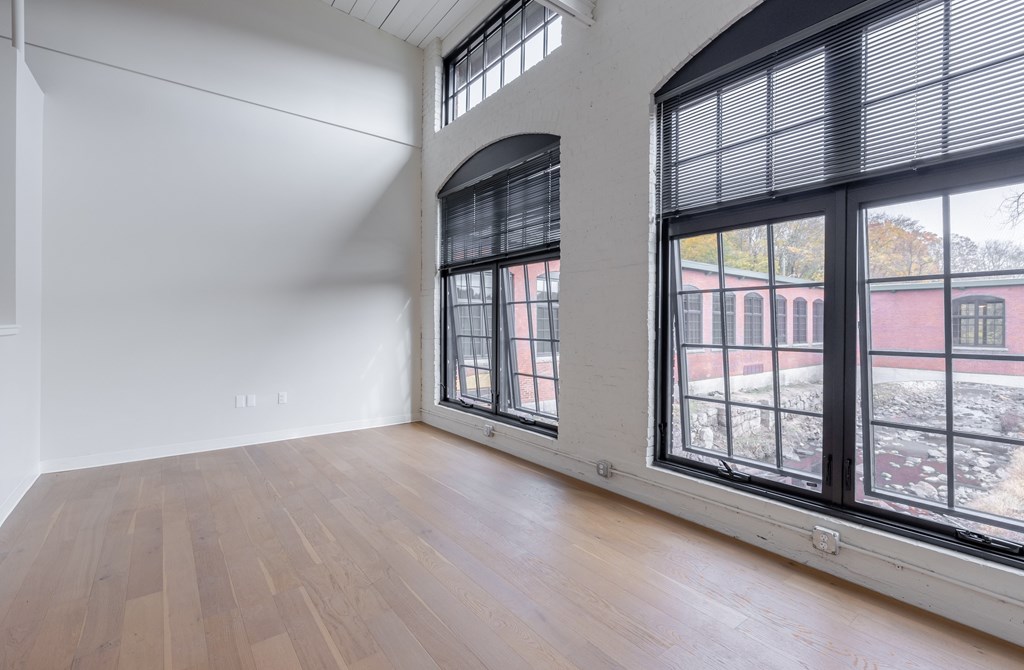 A room with a large window and wooden flooring.