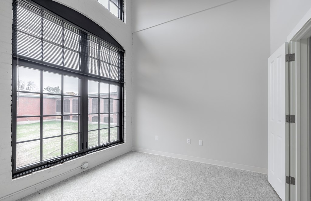 A room with a large window and a carpeted floor.
