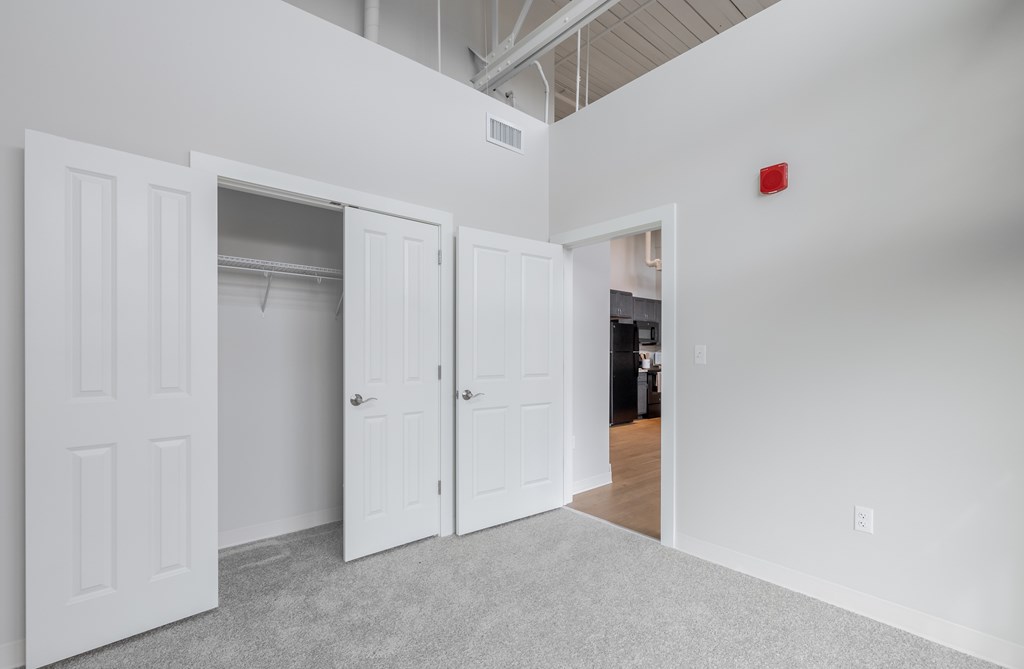 A room with white walls and a grey carpet with three white doors.
