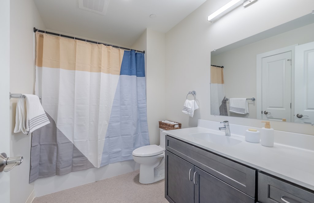 A bathroom with a toilet, sink, and shower curtain.