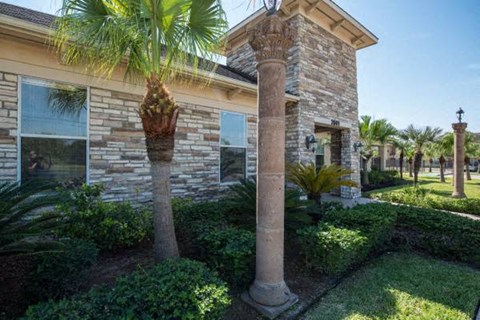 a house with columns and palm trees in front of it