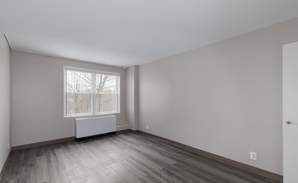 A room with a window and a radiator on the floor.