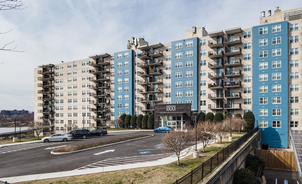A view of a street with cars and apartment buildings.