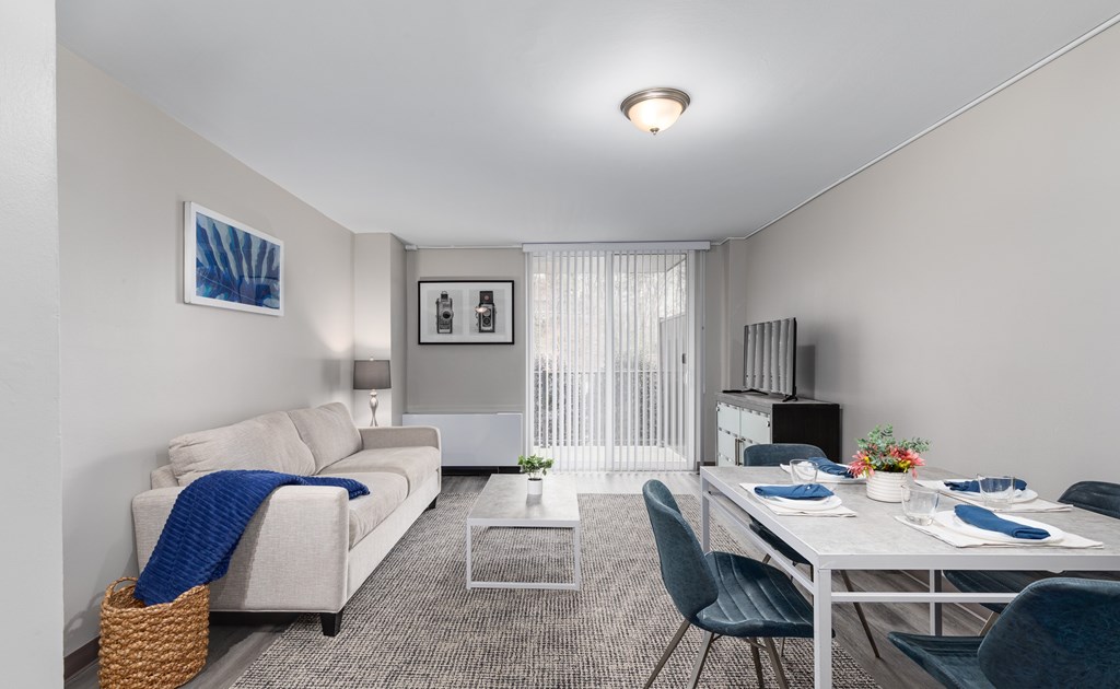 A living room with a couch, a dining table, and chairs.