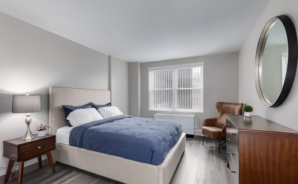 A bedroom with a bed, chair, and lamp.