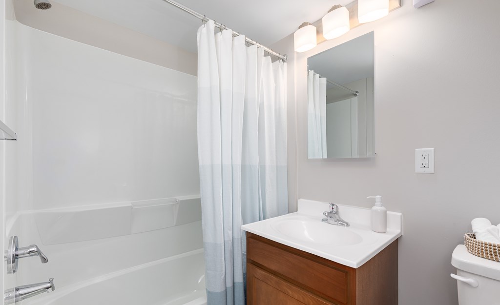 A white sink is on a wooden vanity in a bathroom.