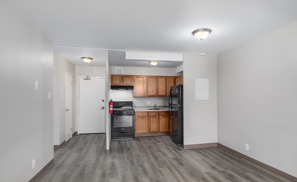 A kitchen with wooden cabinets and a black fridge is visible.