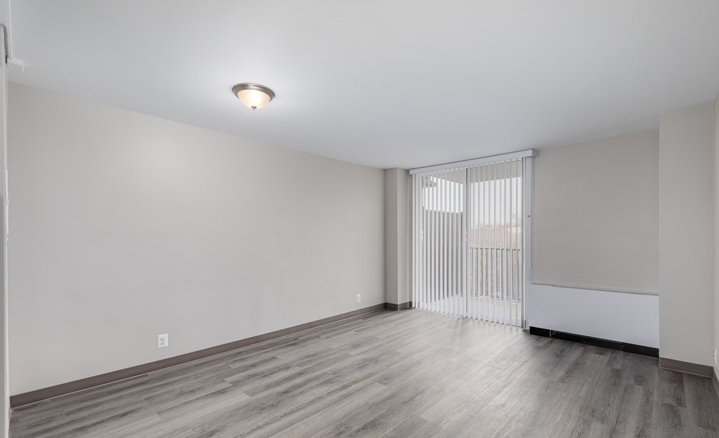 A room with a window covered by white blinds and a light on the ceiling.