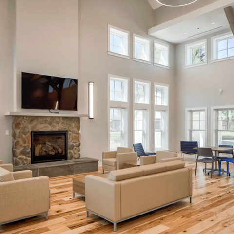 A living room with a stone fireplace and a television mounted above it.