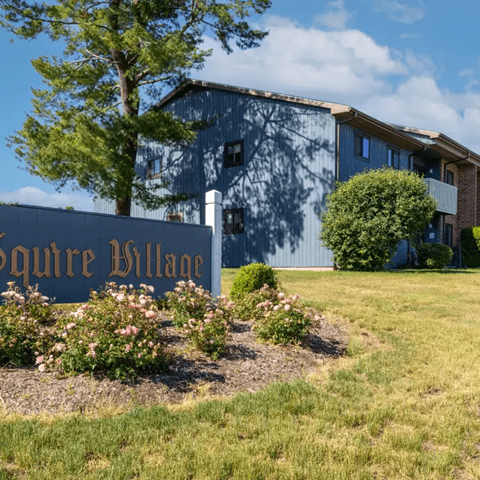 A sign that says "quire Village" in front of a building.