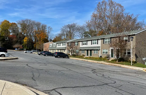 A street view of a residential area with cars parked on the side of the road.