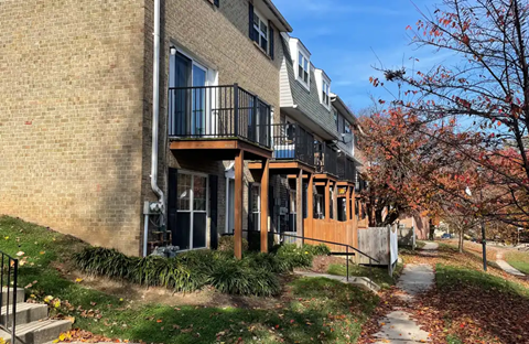 A brick building with a balcony and a tree with red leaves.