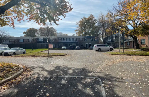 A parking lot with cars and trees with autumn leaves.