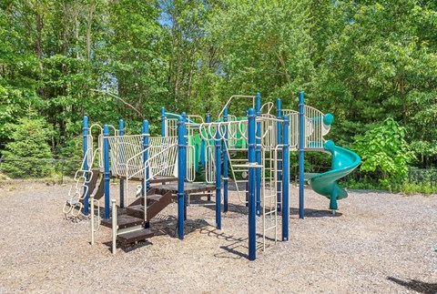 A playground with a green slide and a blue and white structure.