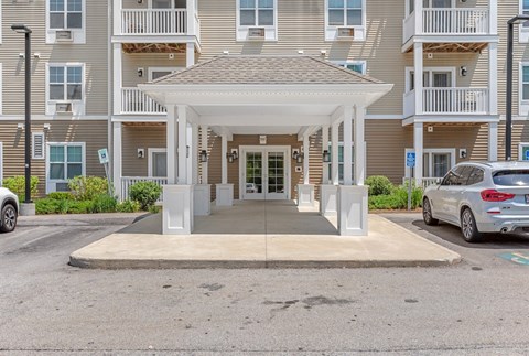 A white covered walkway leads to a building with a white entrance.