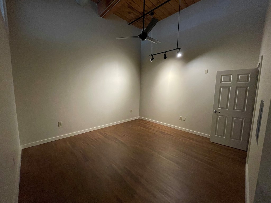 an empty living room with wooden floors and a ceiling fan