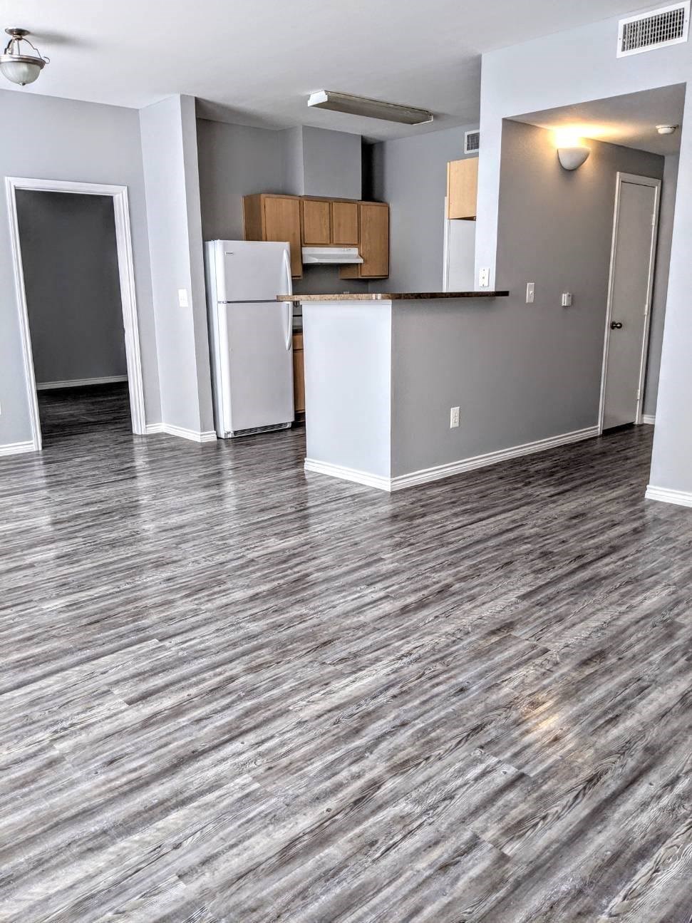 an empty room with a kitchen and a refrigerator